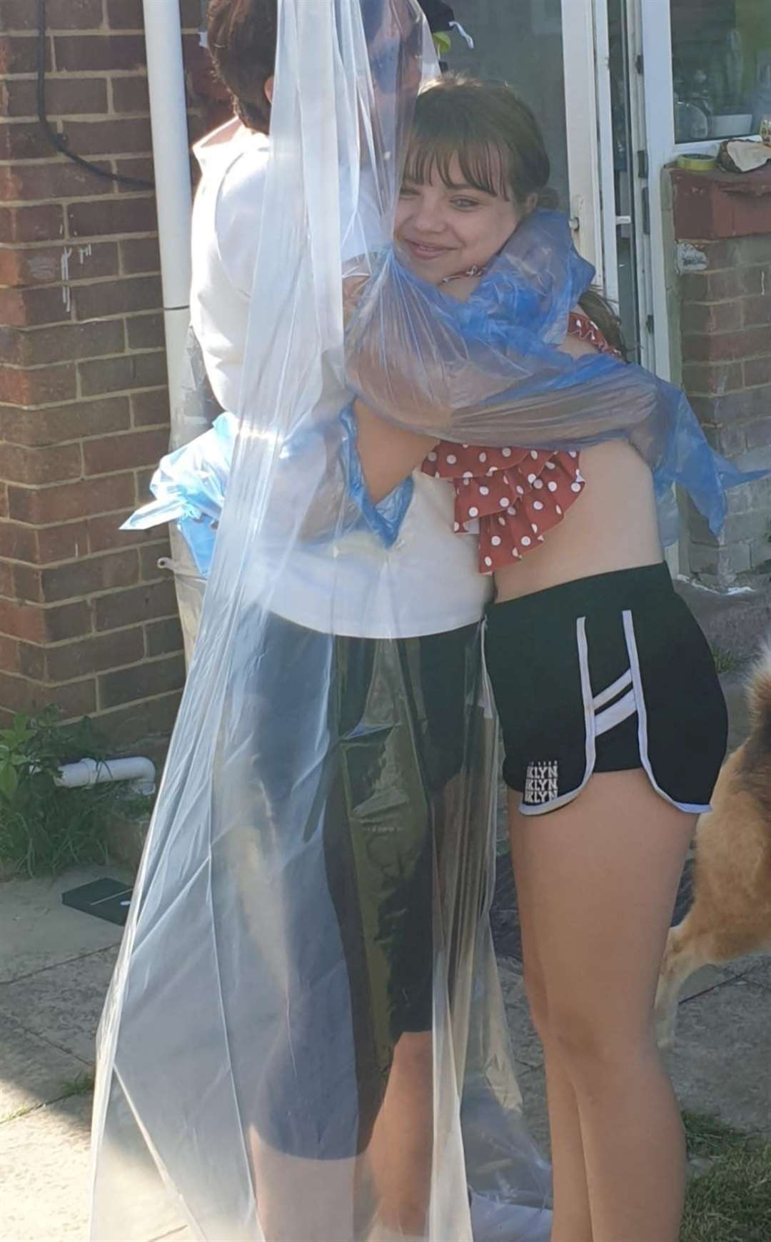 Amber Ewing, 12, gets to hug her grandma after the barrier, made of a shower curtain, was put up in the garden. Picture: SWNS