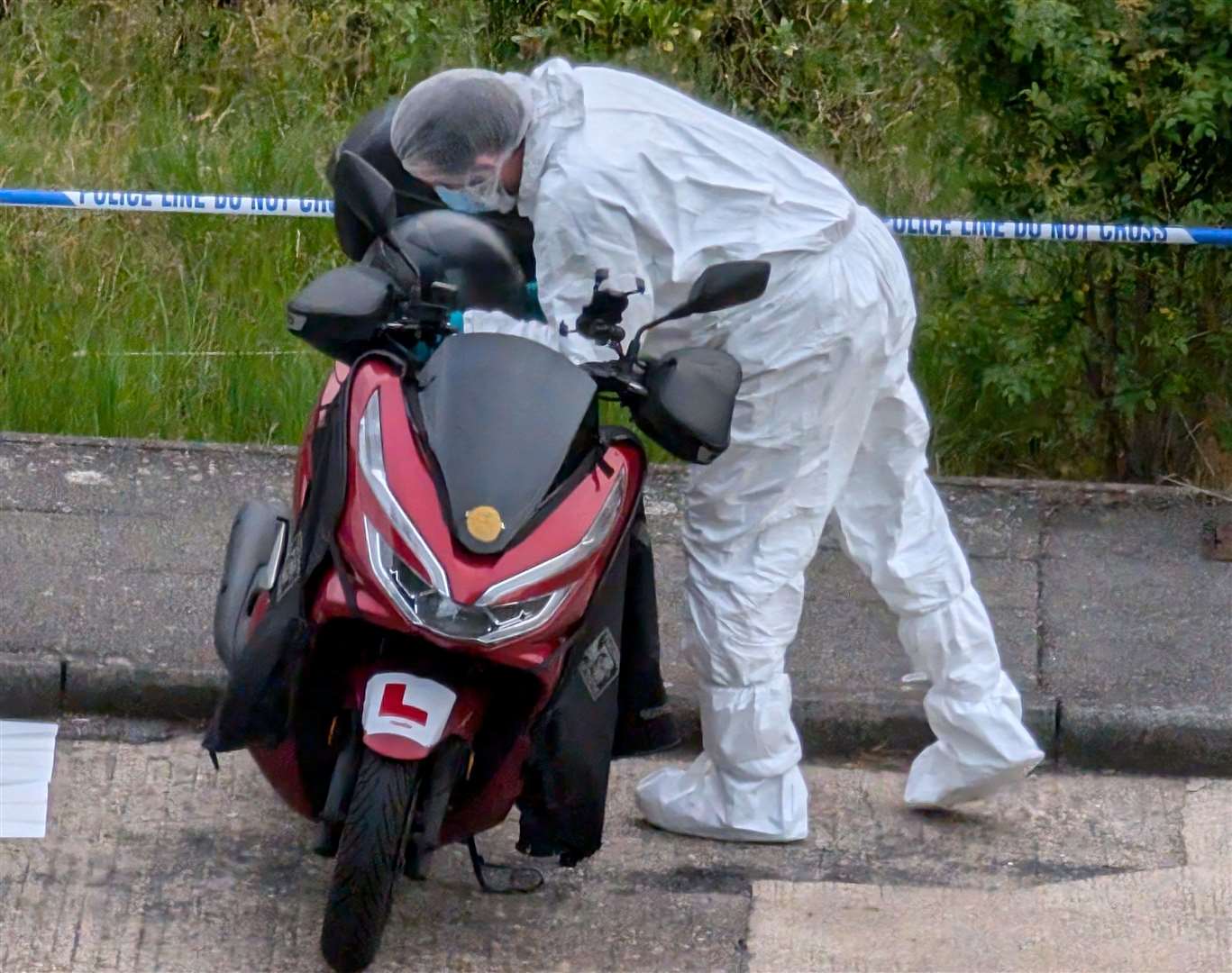 A forensic officer looking at a moped in Mooring Road, Rochester, on Monday evening