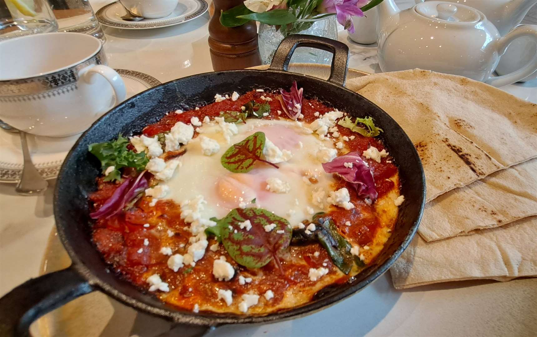 The Shakshuka baked eggs with red peppers and tomatoes seasoned with cumin, smoked paprika, cayenne and spinach leaves with flatbread