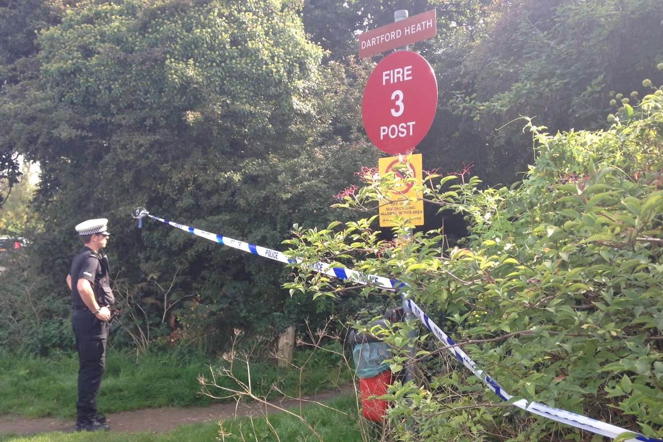 An officer guards the entrance to Dartford Heath after a body was found