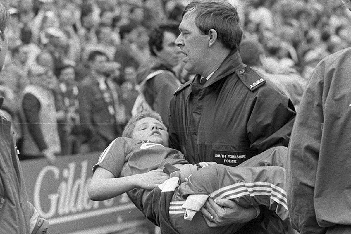 A young fan is carried away by a police officer after being crushed in the Leppings Lane stand at Hillsborough on April 15, 1989. Picture: Ross Parry/Sheffield Star