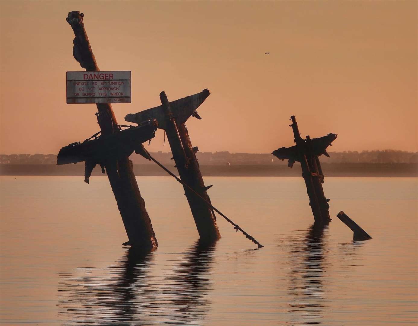 The distinctive masts of the SS Richard Montgomery bomb ship wrecked off Sheerness captured at low tide and at sunset by Margaret Flo McEwan