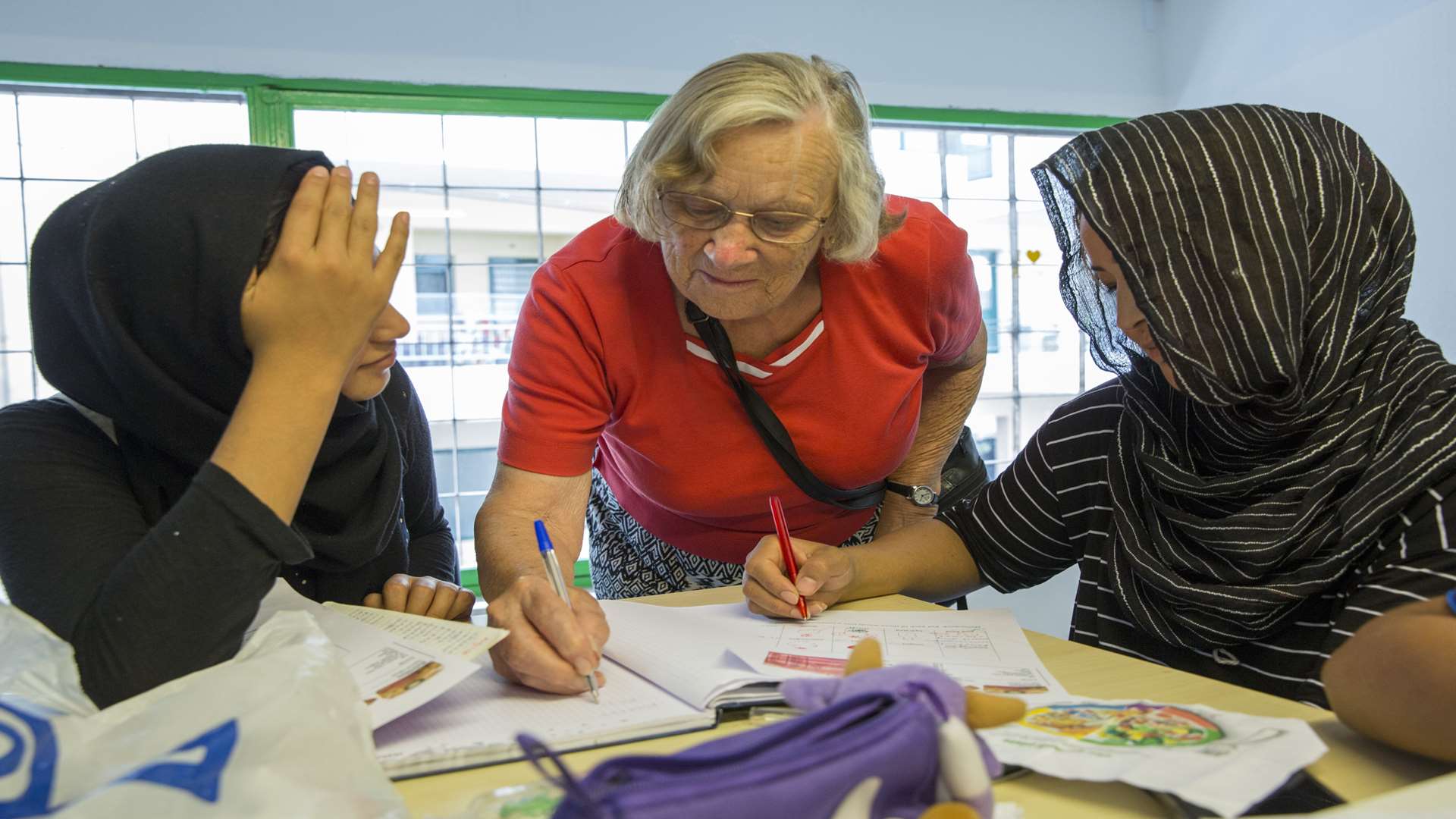 Helping two young women during an English lesson at the Mikri Poli community centre that Oxfam has funded and runs with its partners