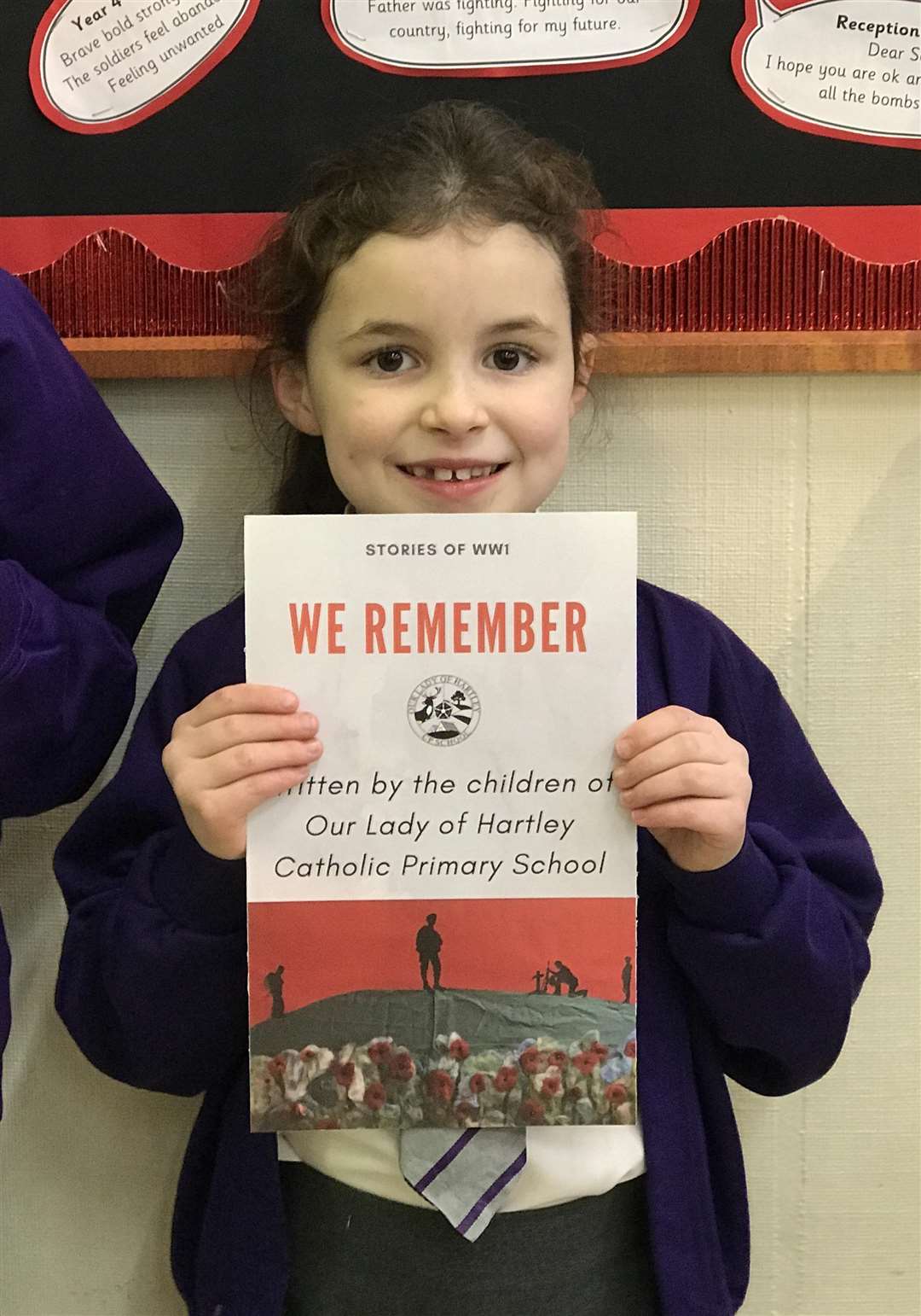 Sophie, eight, with the front cover of Our Lady of Hartley's First World War centenary eBook