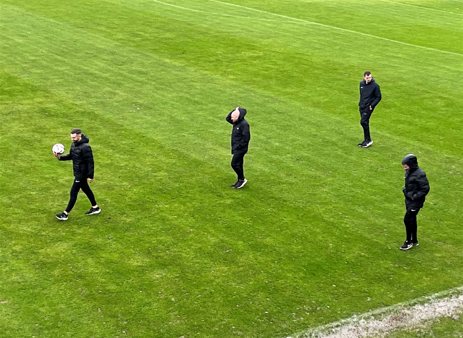 Referee Adam Merchant leads the pitch inspection.