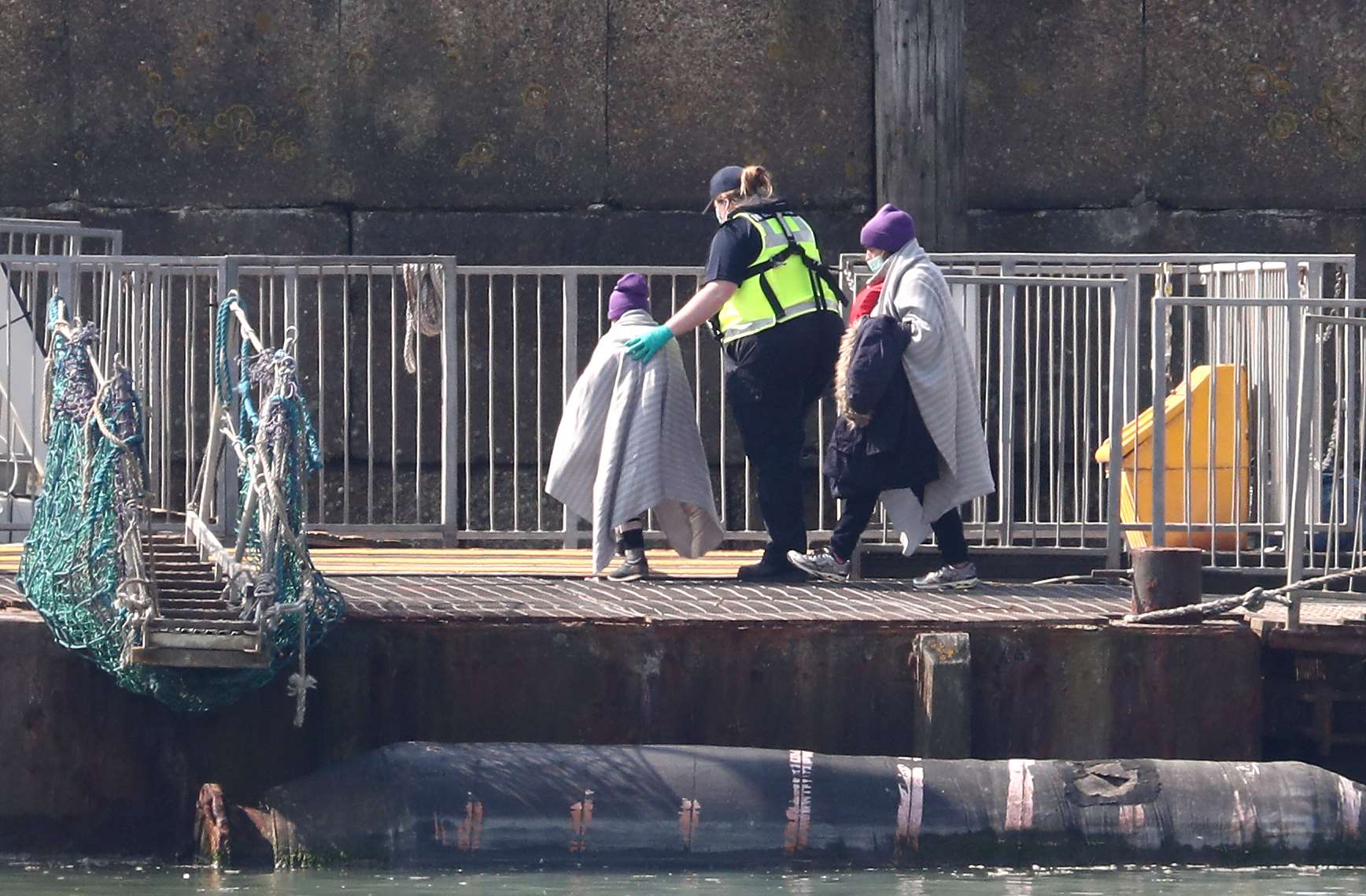 A Border Force officer helps a small child wrapped in a blanket in Dover, Kent (Gareth Fuller/PA)