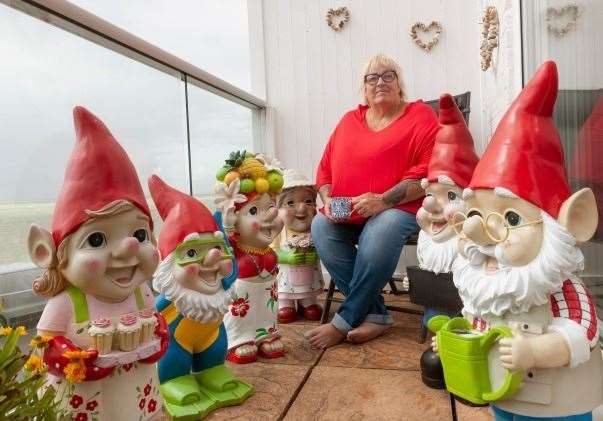 Janet Wilson on her balcony with a collection of cheeky Asda gnomes. Picture: Asda