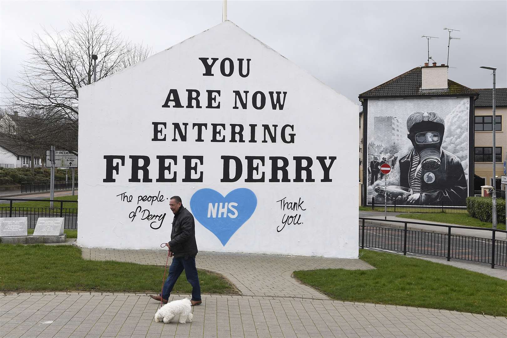 A man walks his dog past a message of support for the NHS on the Free Derry Corner wall in Londonderry (Michael Cooper/PA)