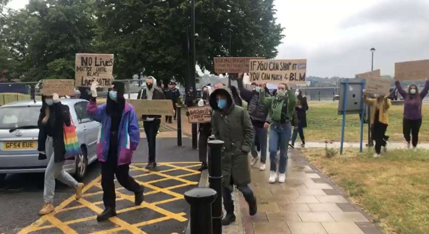 Hundreds of people are marching carrying placards and signs