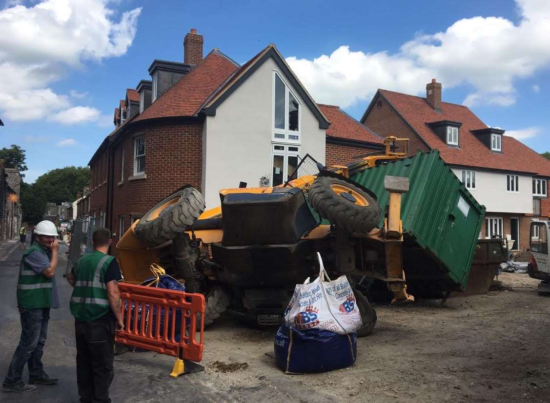 Embarrassed workmen look on at the fallen crane.