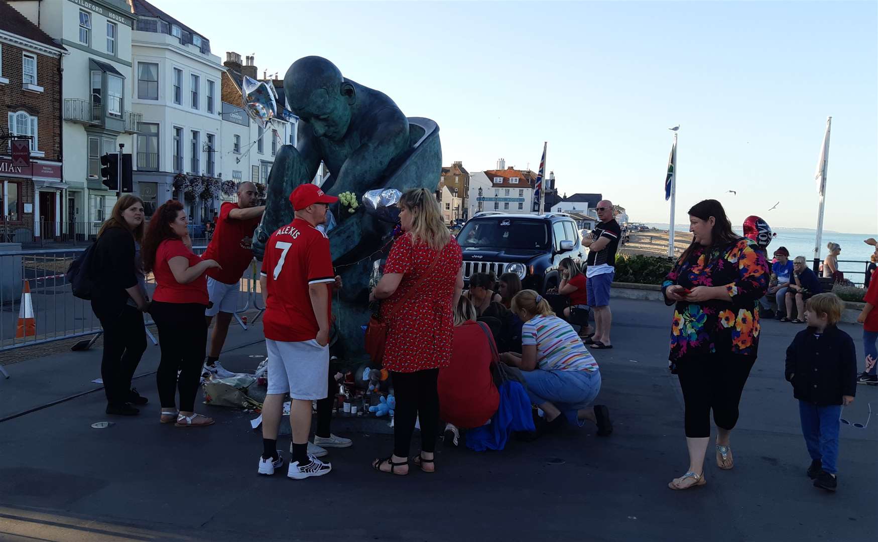 People placing tributes around the pier statues