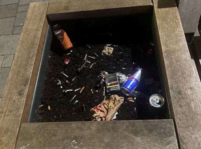 Energy drinks join the cigarette butts discarded in this planter