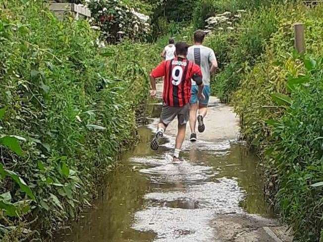 Runners splash through the flooded towpath