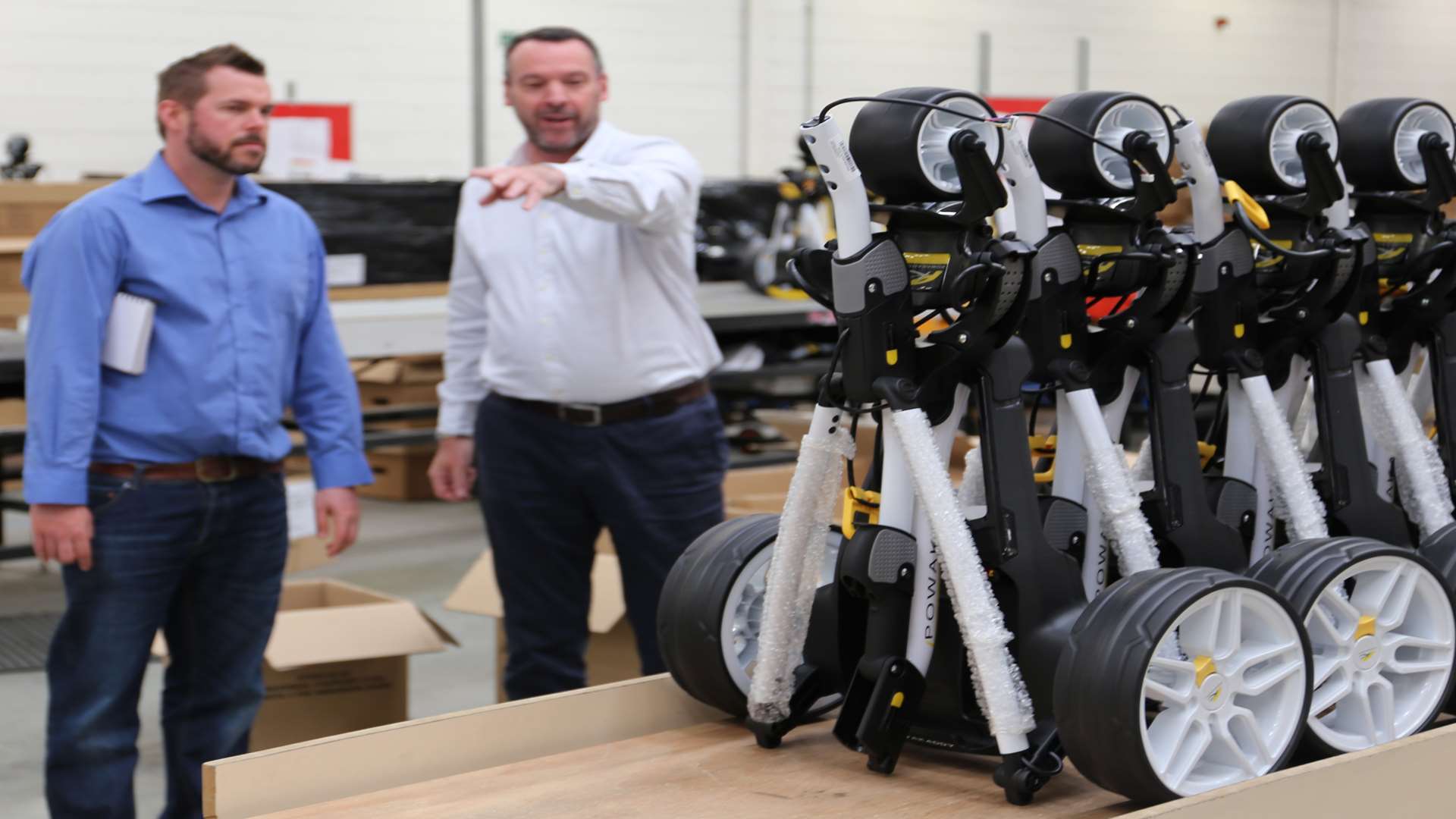 David Catford, right, leads a tour of the PowaKaddy warehouse in Sittingbourne