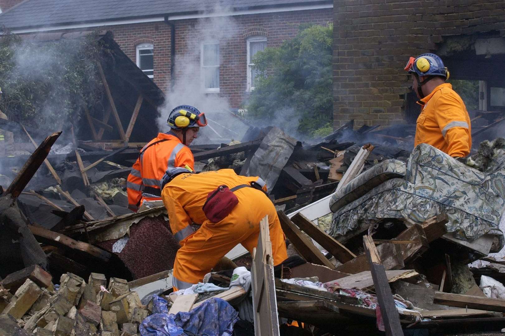 Firefighters search through the smouldering remains of one house