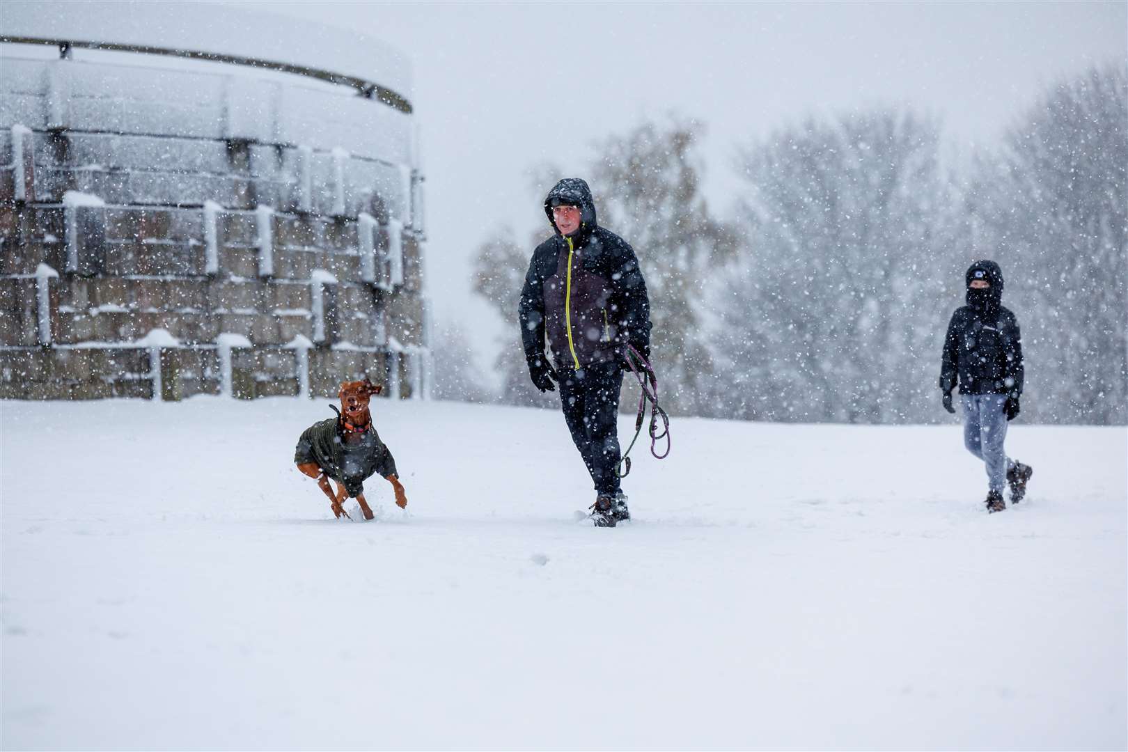 A man and his son and dogs having fun in heavy snowfall at Bannockburn, near Stirling (Robert Perry/PA)