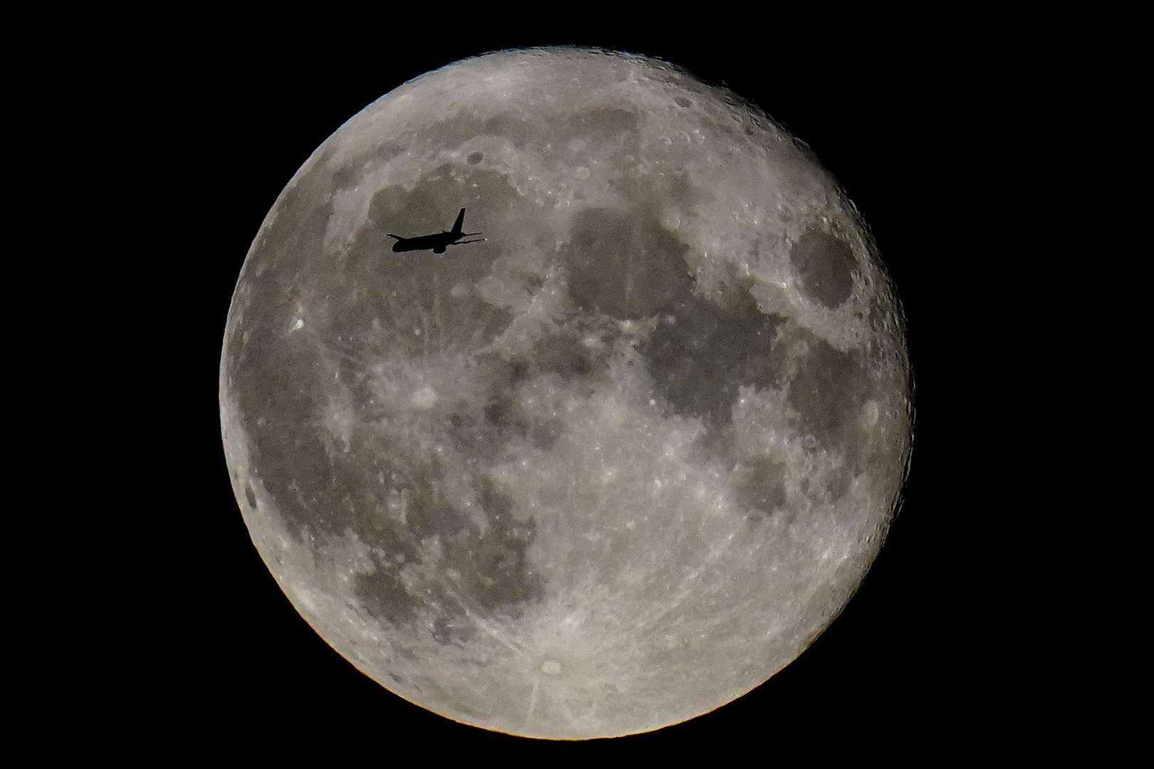 A plane passes in front of a supermoon (Victoria Jones/PA)