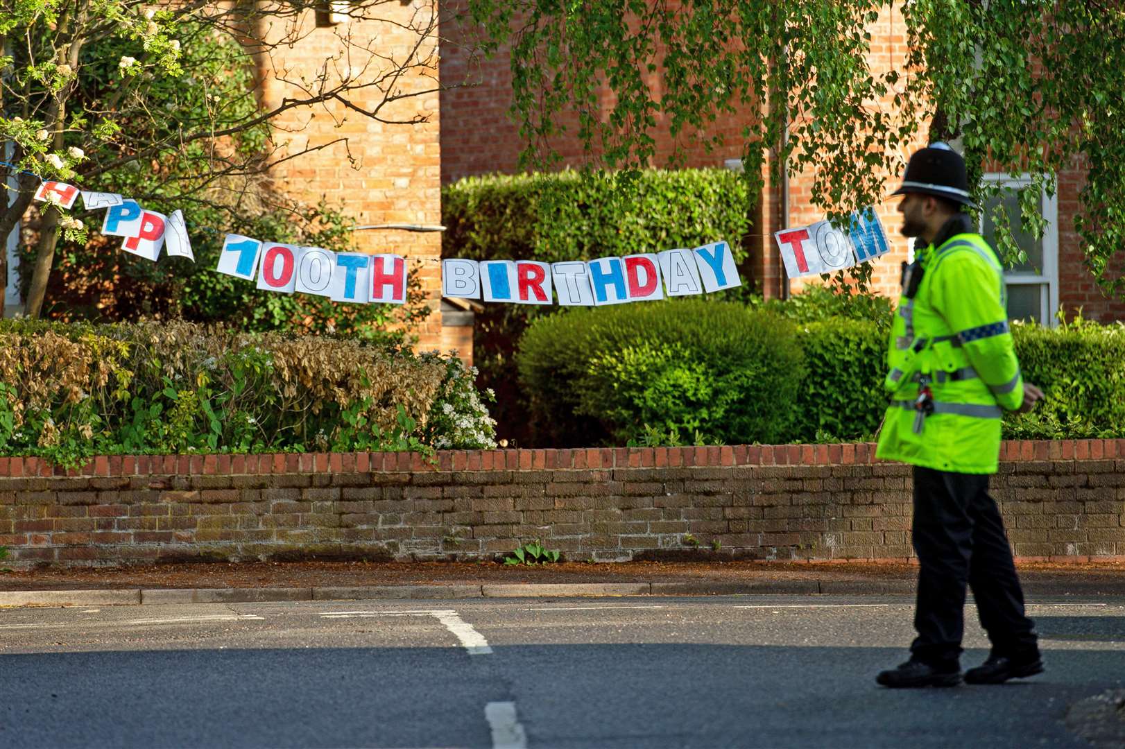 A policeman passes a Happy Birthday banner to mark the 100th birthday of Second World War veteran Captain Tom Moore close to his home in Marston Moretaine, near Bedford (Joe Giddens/PA)