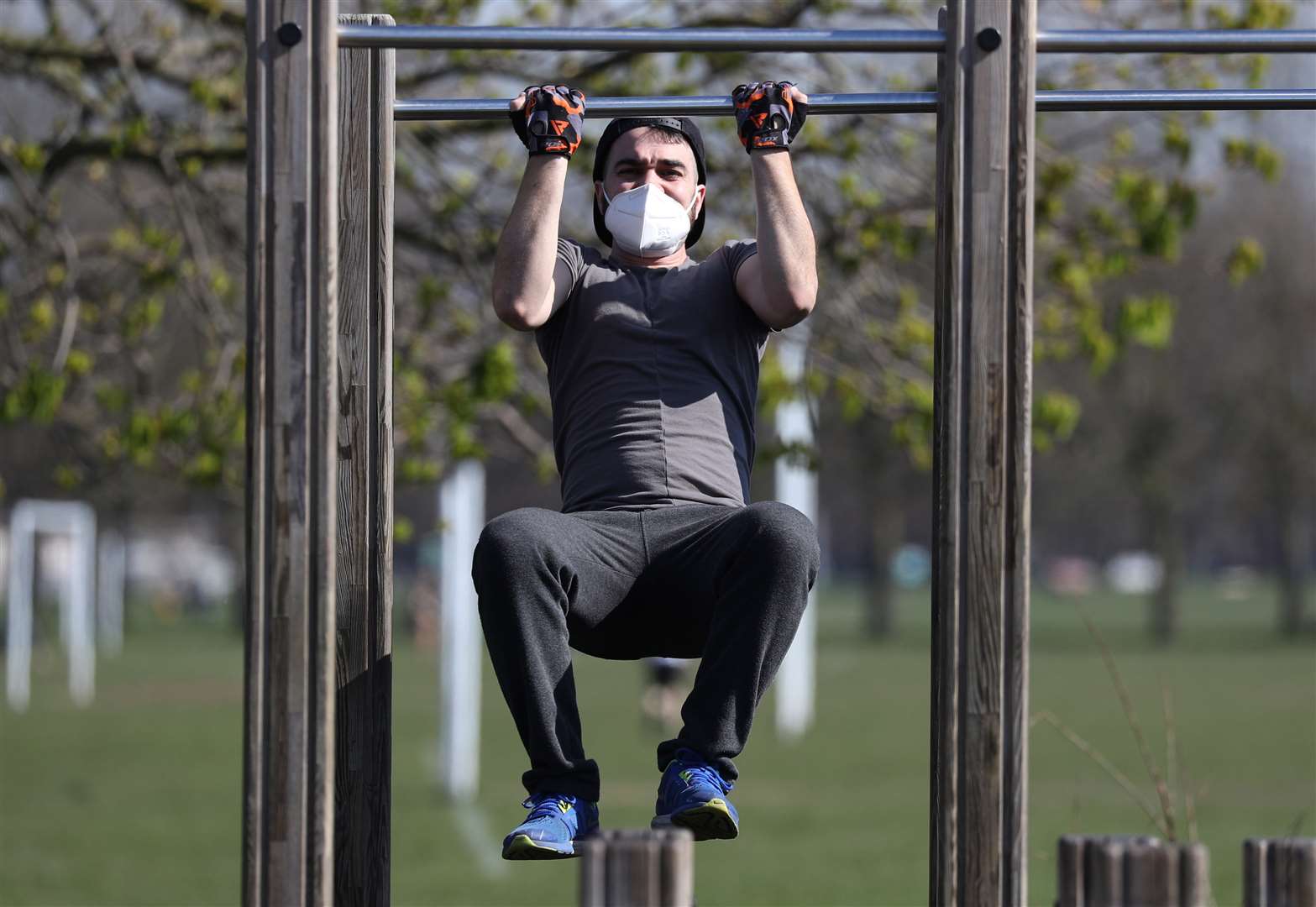 A visitor to an outdoor gym wears a mask while exercising on Clapham Common, London (Jonathan Brady/PA)