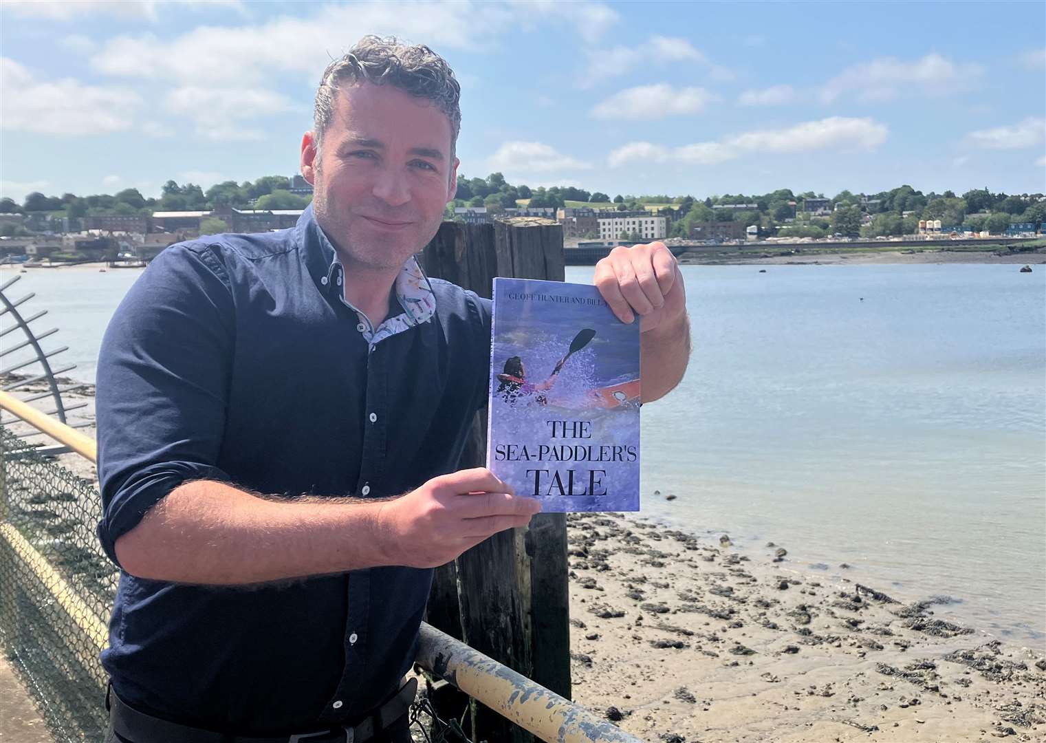 Geoff's nephew and KM Group reporter Chris Hunter, with a copy of a Sea Paddler's Tale, next to the Medway where Geoff first set out on his voyage