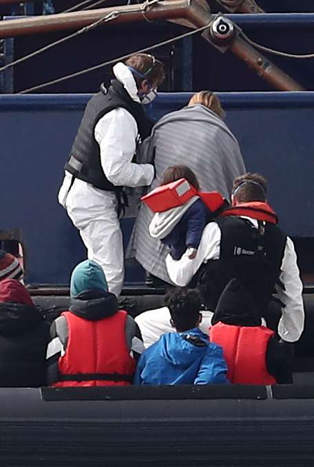 Border Force officers help a woman and child ashore (Gareth Fuller/PA)