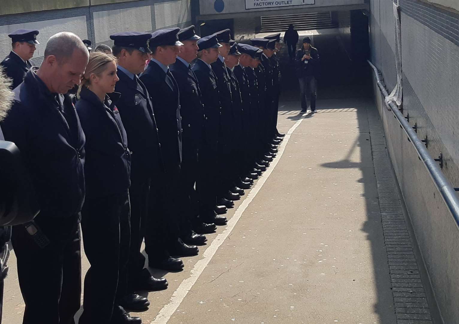 Firefighters in a land stand to attention in front of the plaque