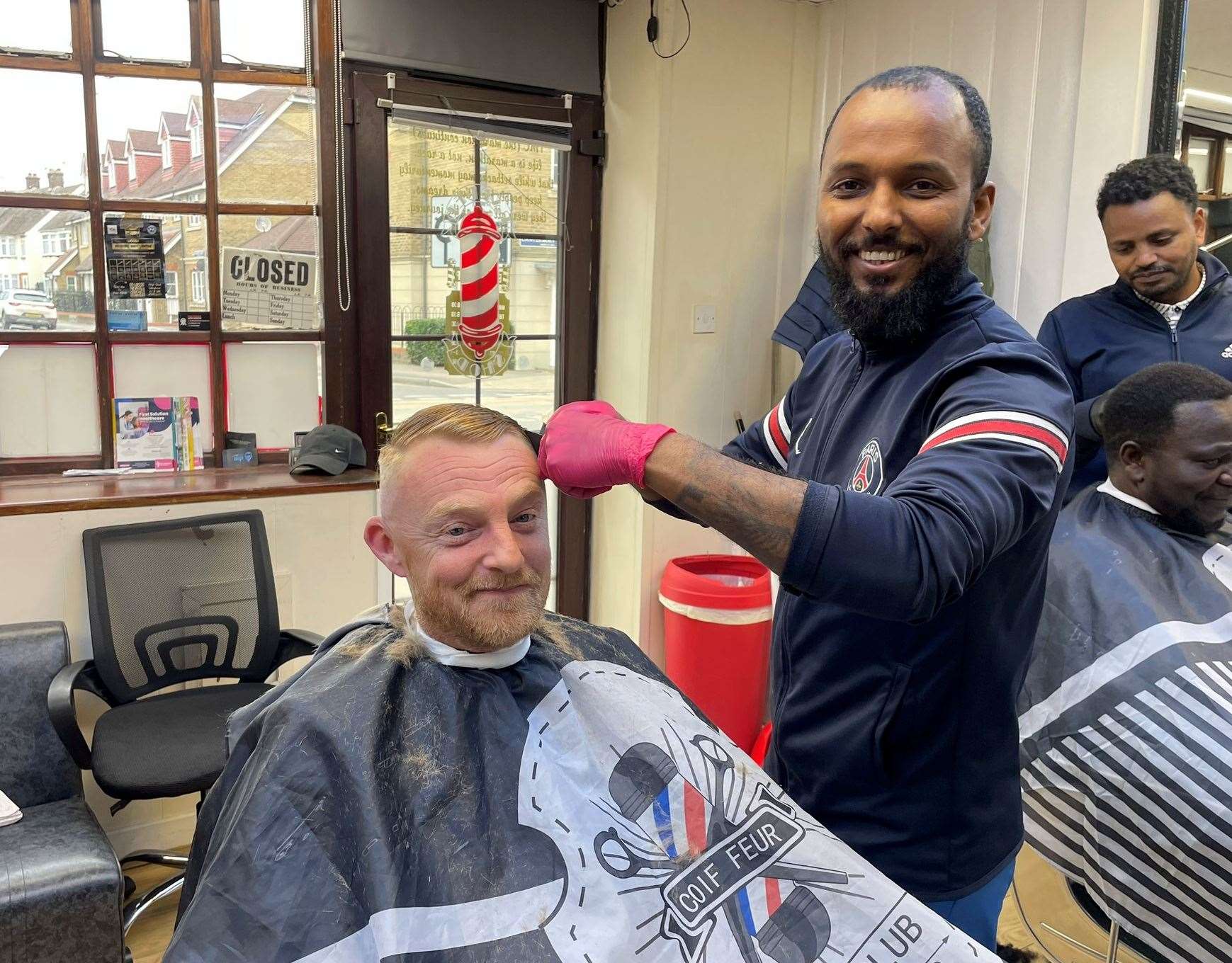 Aman Tuku, owner of TMC Barbers in Sittingbourne, with customer Darren Overy. Picture: Joe Crossley