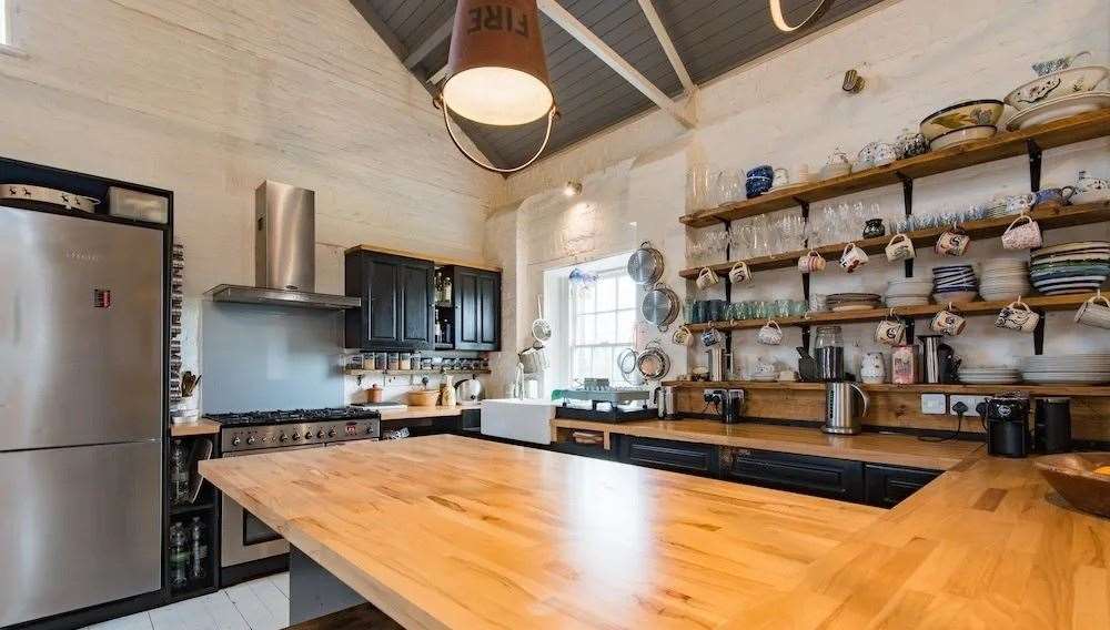 Business owners Elvis and Kresse Wesling converted the house in 2013 using recycled materials, including the kitchen's bucket lights. Picture: Unique Property Company