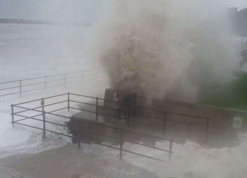 The boys duck against the wall as a huge wave rises above them