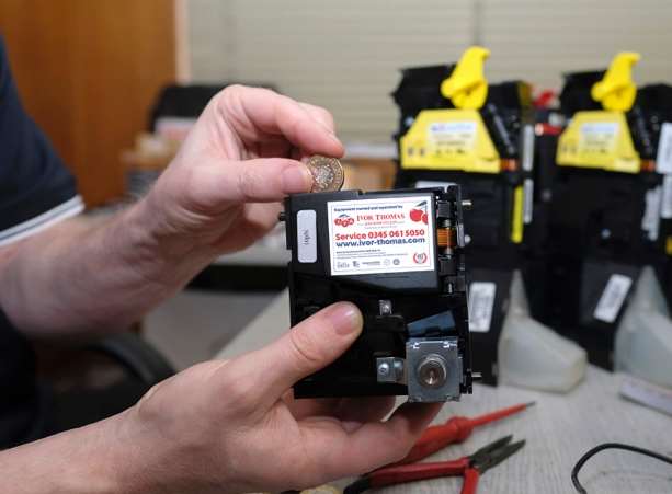 An Ivor Thomas engineer adapting a coin mechanism to fit the new £1 coins