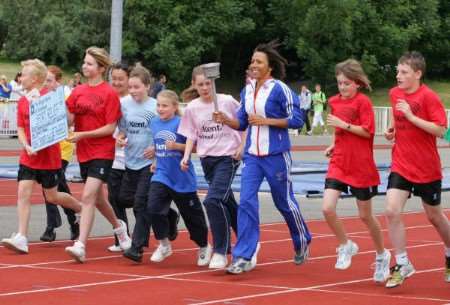 Kelly Homes runs into the stadium with children at the Kent School Games