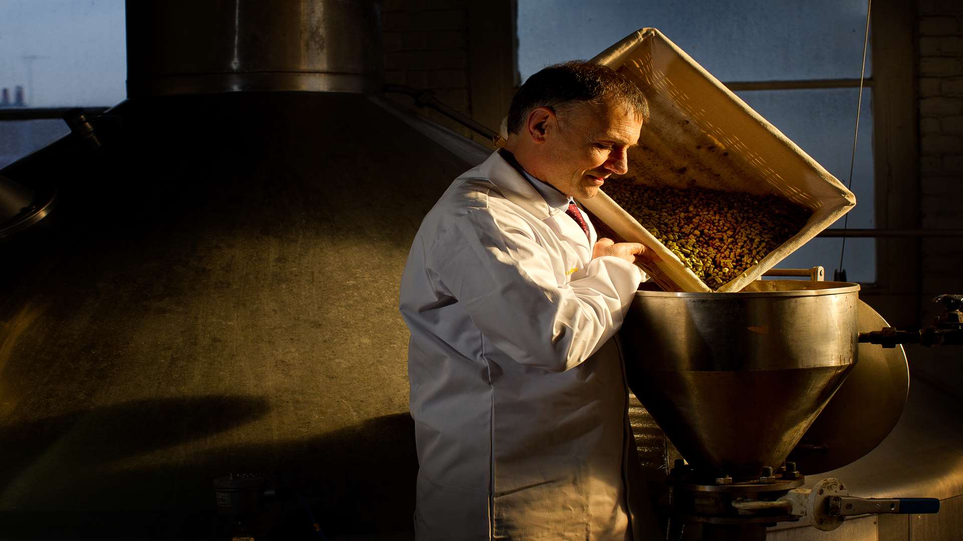 Head brewer Richard Frost pours hops into the copper