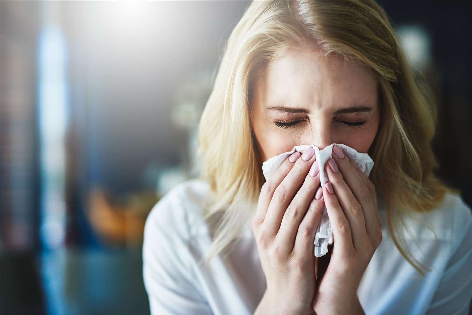 Shot of a frustrated businesswoman using a tissue to sneeze in while being seated in the office. (22461471)