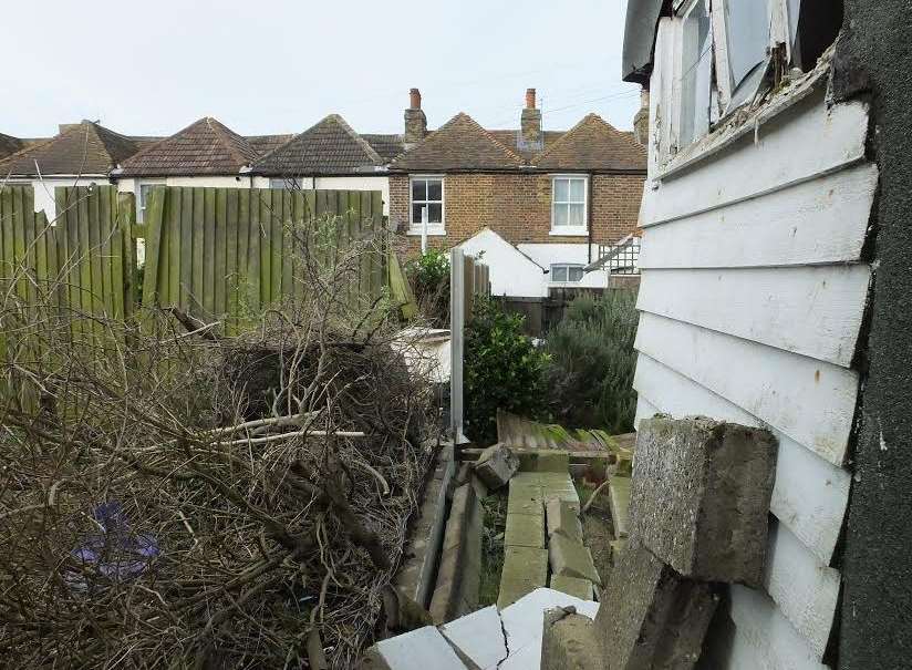 The wall fell against the shed smashing the window