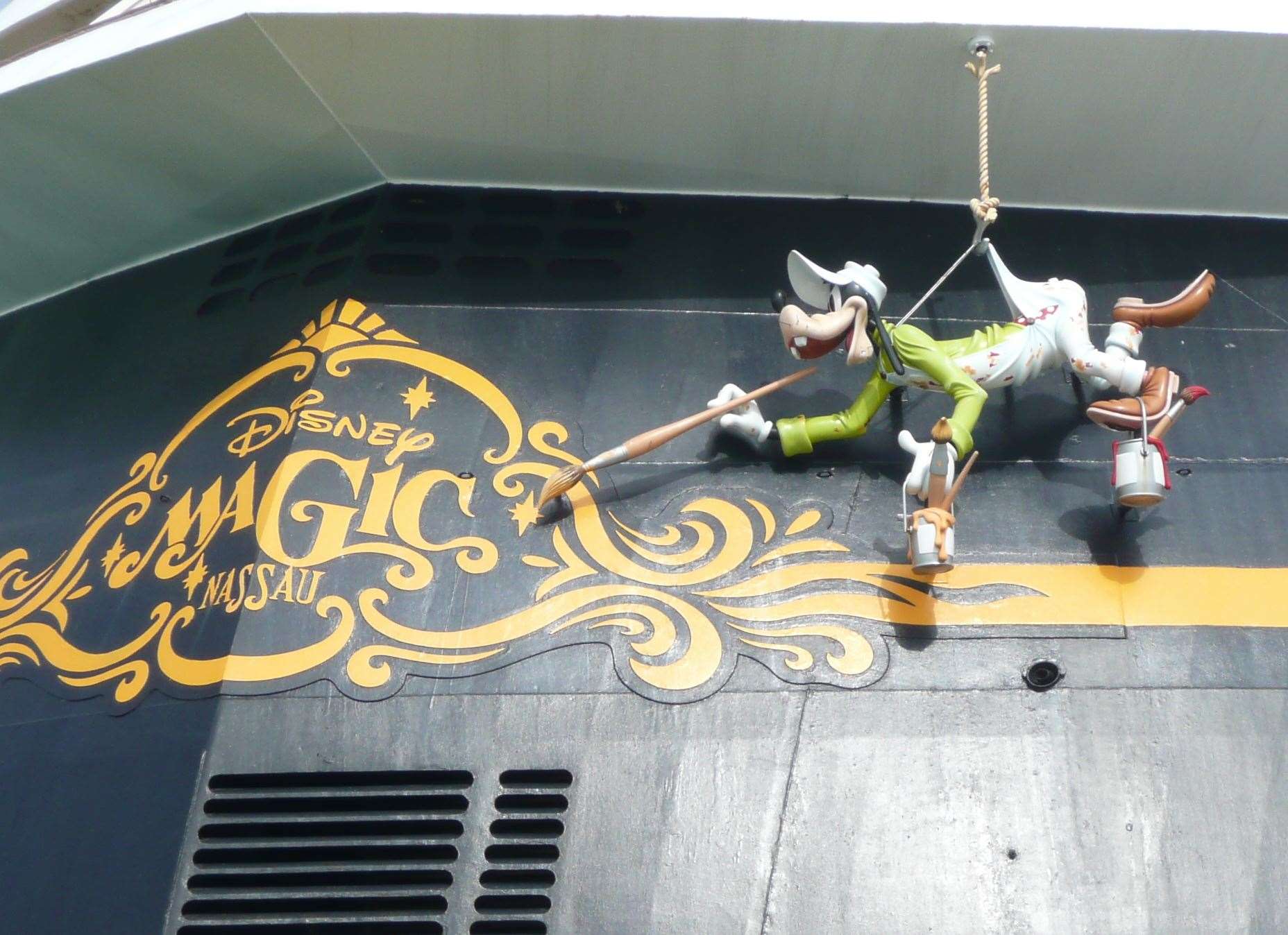 A massive hanging Goofy hand-painting the ship's name on the stern