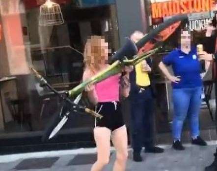 People watched on as the woman picked up a bike outside KFC and appeared to try and throw it