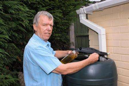 John Crockford adds olive oil to his water butt, where he says he found thousands of mosquitoes