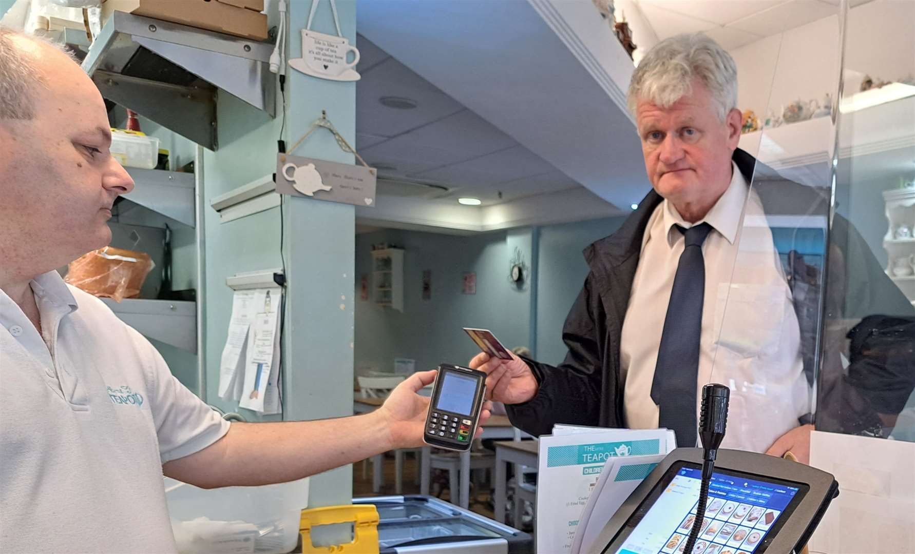 Reporter Sam Lennon making a contactless payment with a credit card. Pictured with him at The Little Teapot in Park Mall, Ashford, is café owner Russell Geen