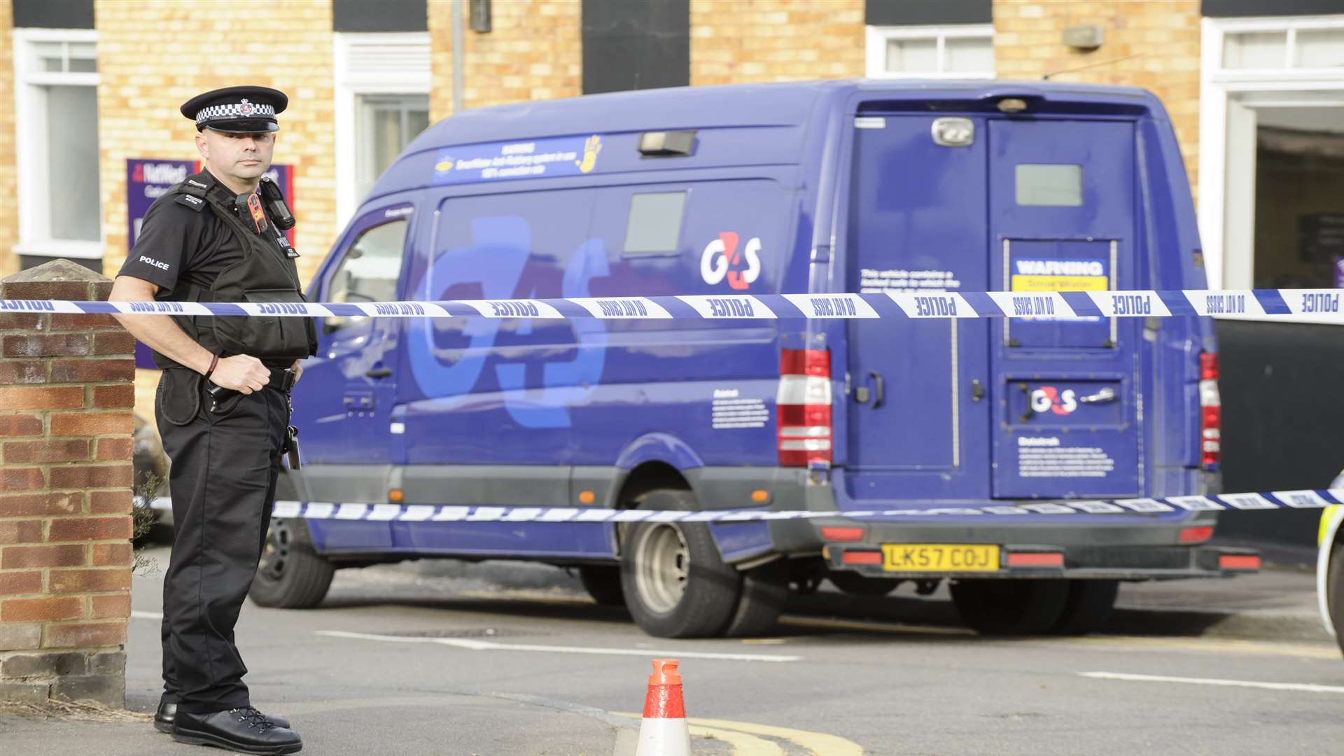 A police officer stands guard at the edge of the cordon